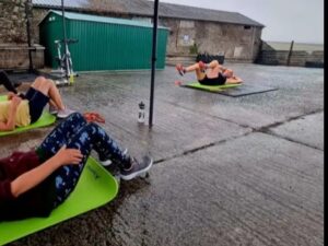 Three women performing ab exercises on yoga mats at Farming Fit