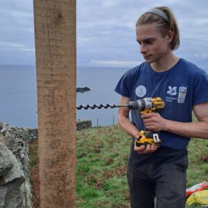 Image of man using a drill on a fingerpost sign