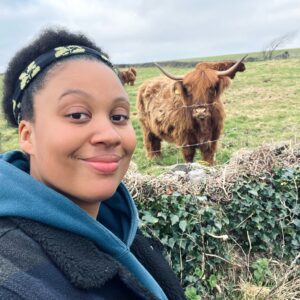 woman taking selfie with cow in background
