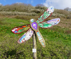 A large, multi-coloured dragonfly sculpture.