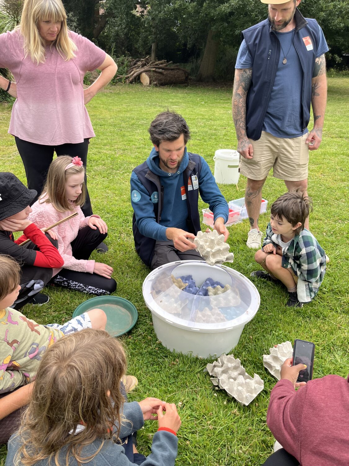 A group of volunteers gathered around a moth trap looking at moths and releasing them safely.