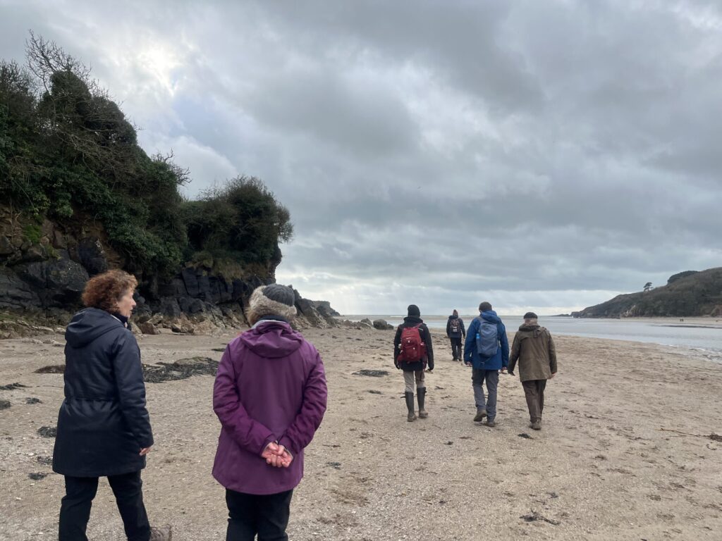 A group of people walking on a beach at a river estuary