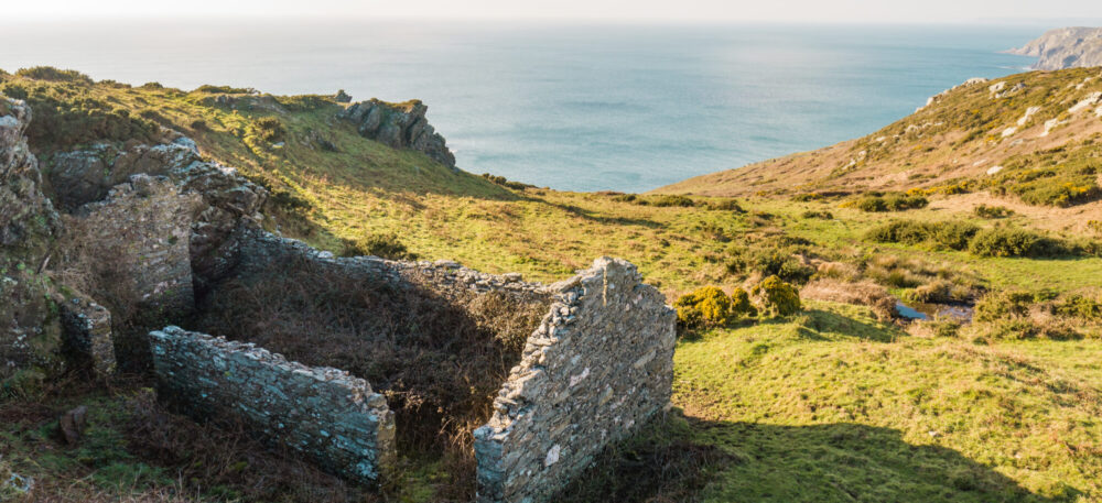 views over valley to coast with remains of a stone barn in the foreground