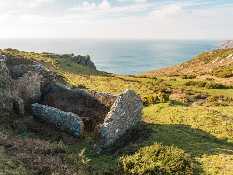 views over valley to coast with remains of a stone barn in the foreground