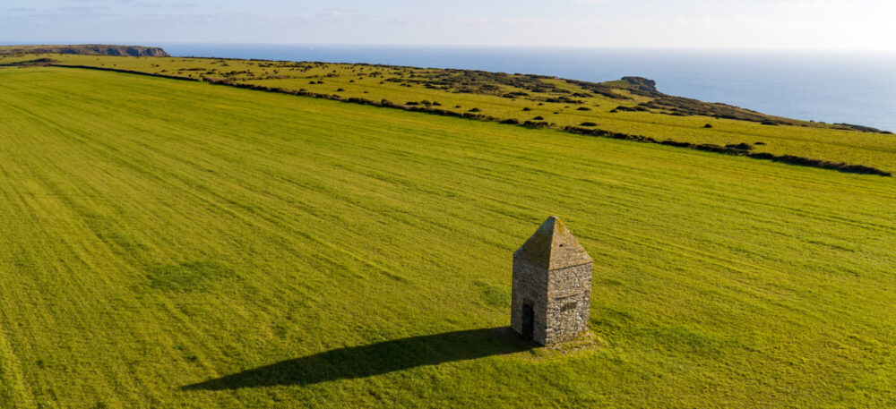 view across plateau to sea with a square stone built tower