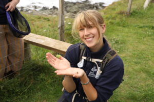 an image of a person smiling at the camera holding a small bee
